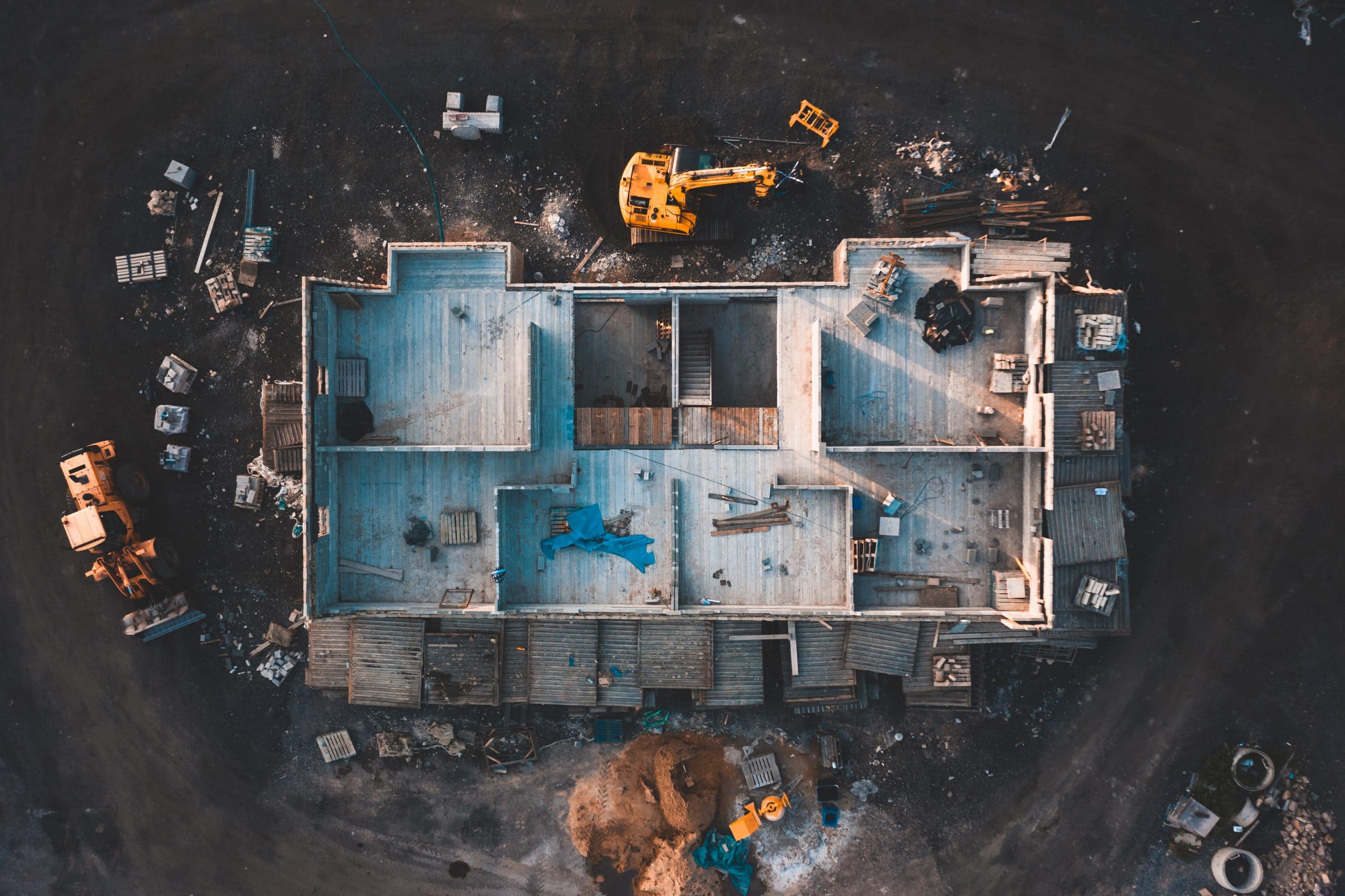 Structural engineer and architect working with blueprints discuss at the outdoors construction site.