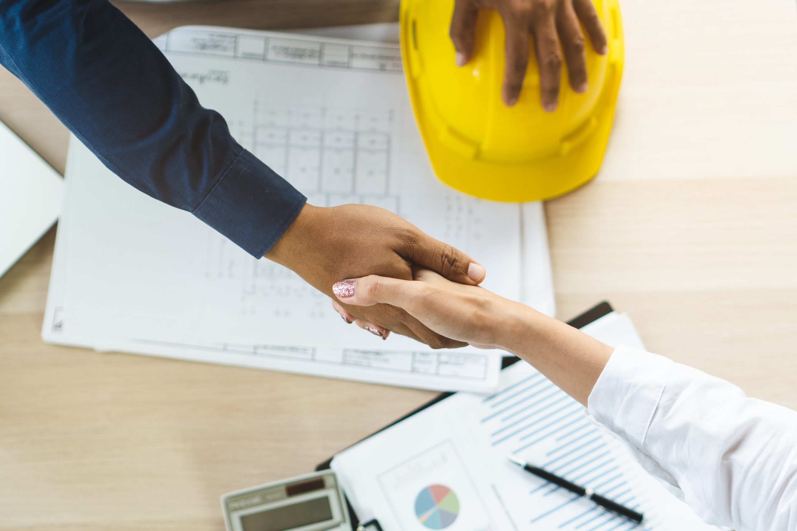 Structural engineer and architect working with blueprints discuss at the outdoors construction site.